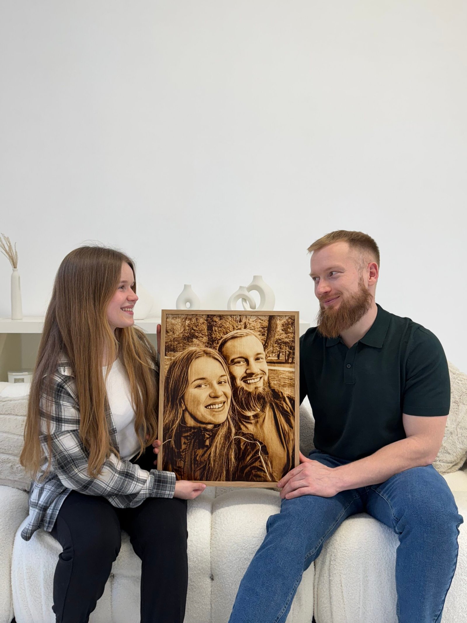 Para siedząca razem i trzymająca personalizowany portret na drewnie